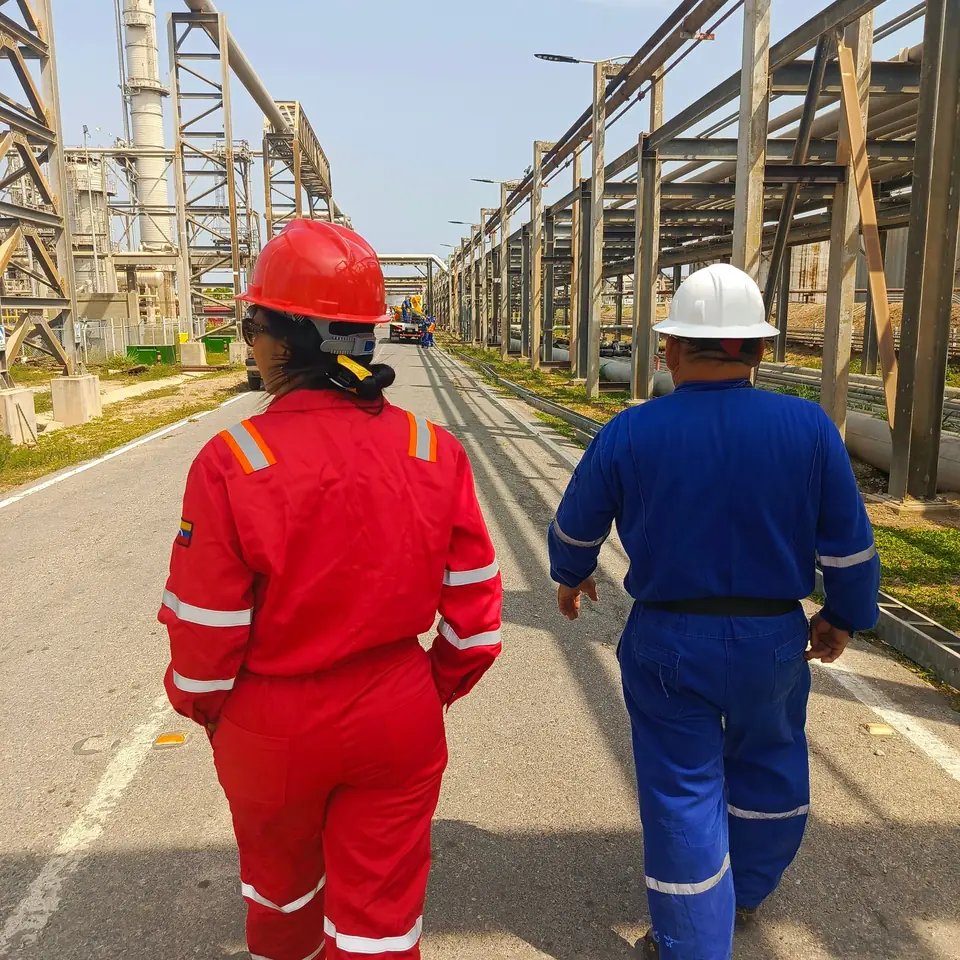 Equipe de macacão caminhando em uma planta de processo