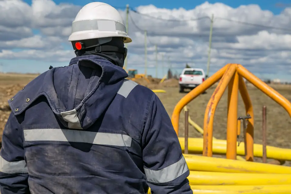 Trabalhador de capacete ao lado de dutos de gás